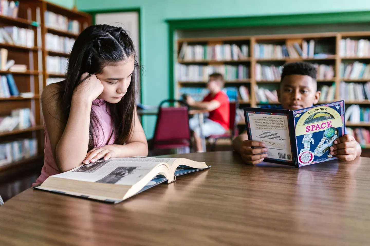 Estudiantes leyendo en una mesa de biblioteca
